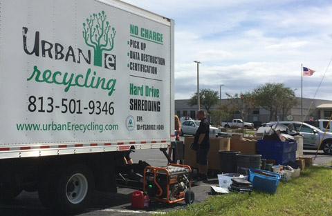 People loading paper into shredder truck at curbside