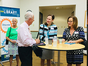 Group of adults standing around a small round table